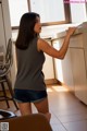 A woman standing in a kitchen next to a window.