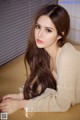 A woman with long brown hair laying on a bed.