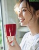 A woman holding a red cup with steam coming out of it.