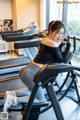 A woman sitting on a stationary bike in a gym.