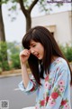 A woman with long brown hair wearing a blue floral shirt.