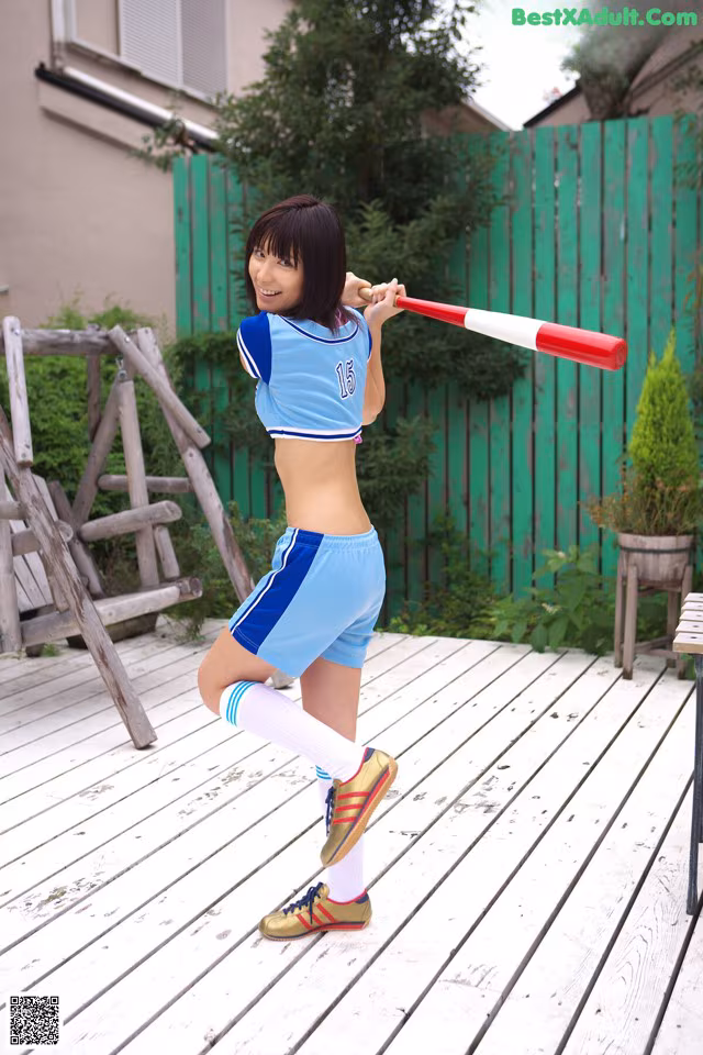 A woman in a blue and white outfit holding a baseball bat.