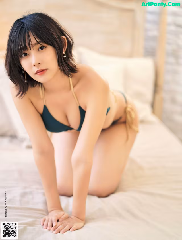 A woman in a bikini sitting on a bed.