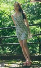 A woman in a floral dress standing on a bridge.