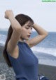 A woman in a blue top is standing on the beach.