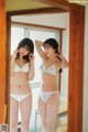 A woman in a white bra and panties standing in front of a mirror.