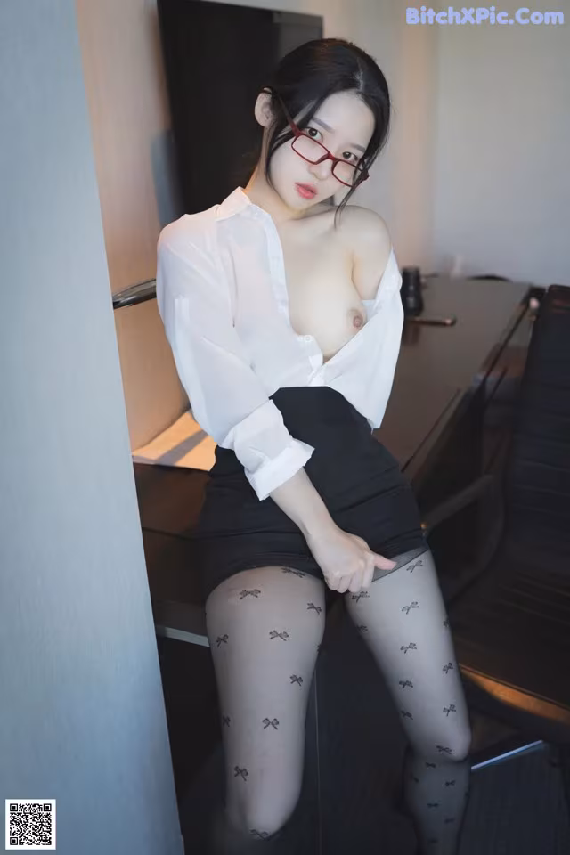 A woman in a white shirt and black skirt posing for the camera.
