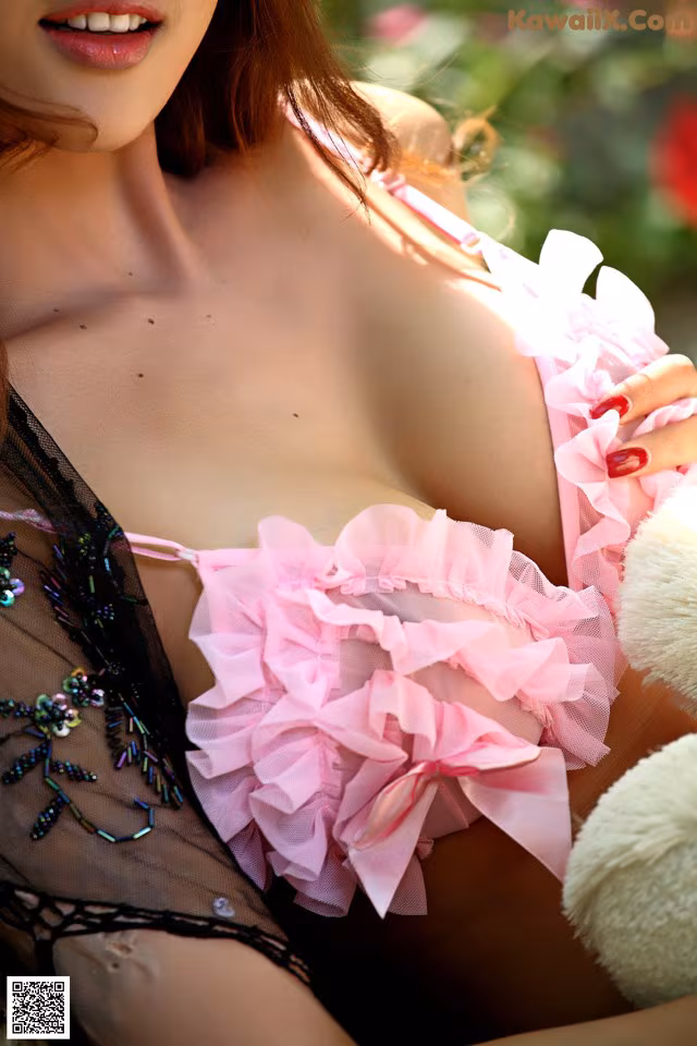 A woman in a pink lingerie holding a teddy bear.