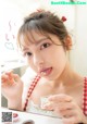 A woman in a red and white checkered dress holding a jar of candy.