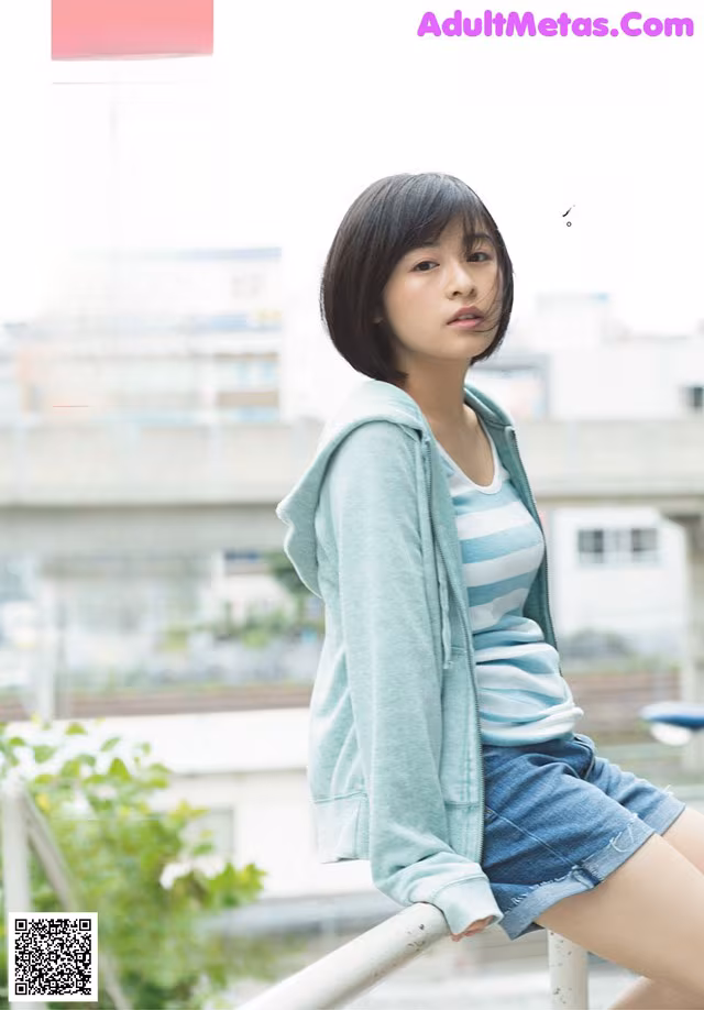 A woman sitting on top of a railing next to a building.