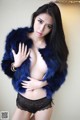 A woman in a blue fur coat posing for the camera.