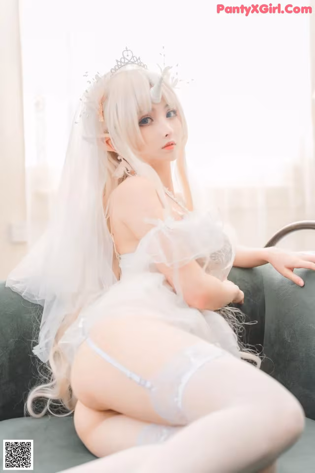 A woman in a wedding dress sitting on a couch.
