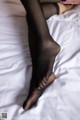 A woman in black stockings is laying on a bed.