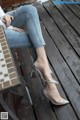 A woman sitting on a wooden bench wearing a pair of silver shoes.