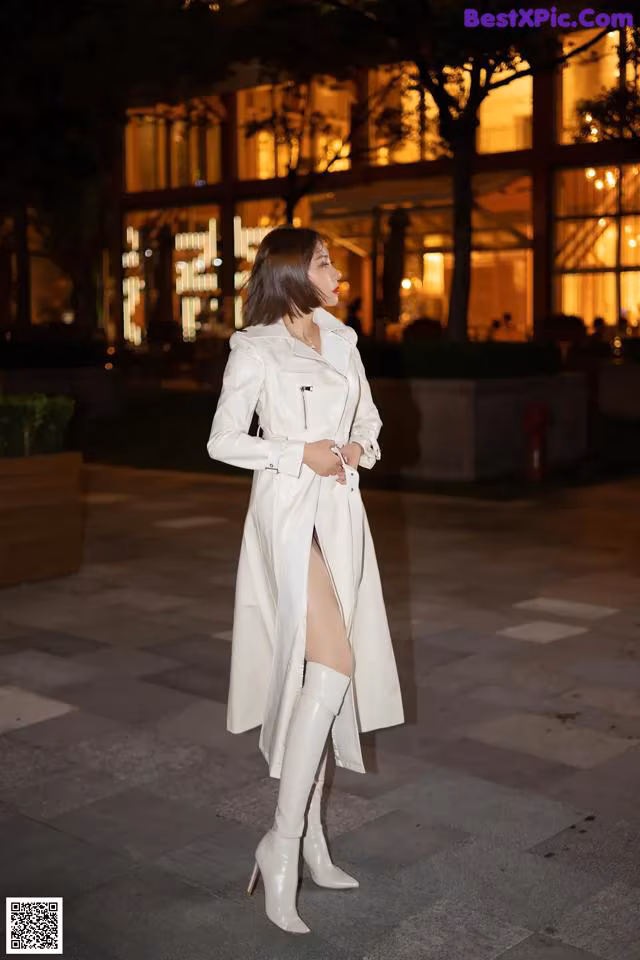 A woman in a white trench coat and thigh high boots.