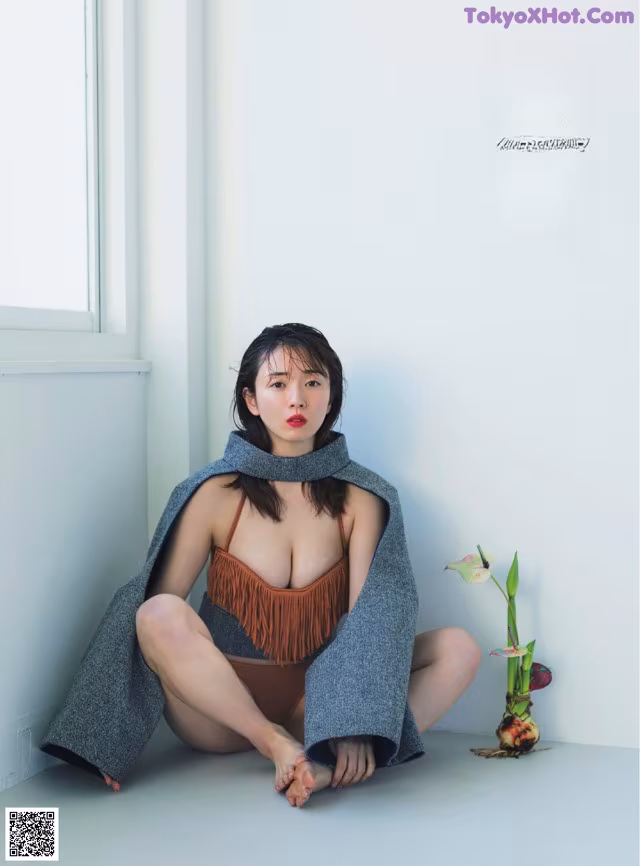 A woman sitting on the floor in front of a window.