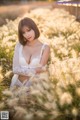 A woman sitting in a field of tall grass.