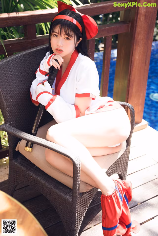 A woman in a red and white outfit sitting on a chair.