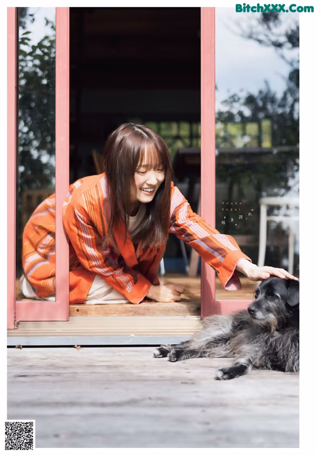 A woman sitting on the ground next to a dog.