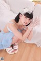 A woman in a blue dress and white gloves crouching on the floor.